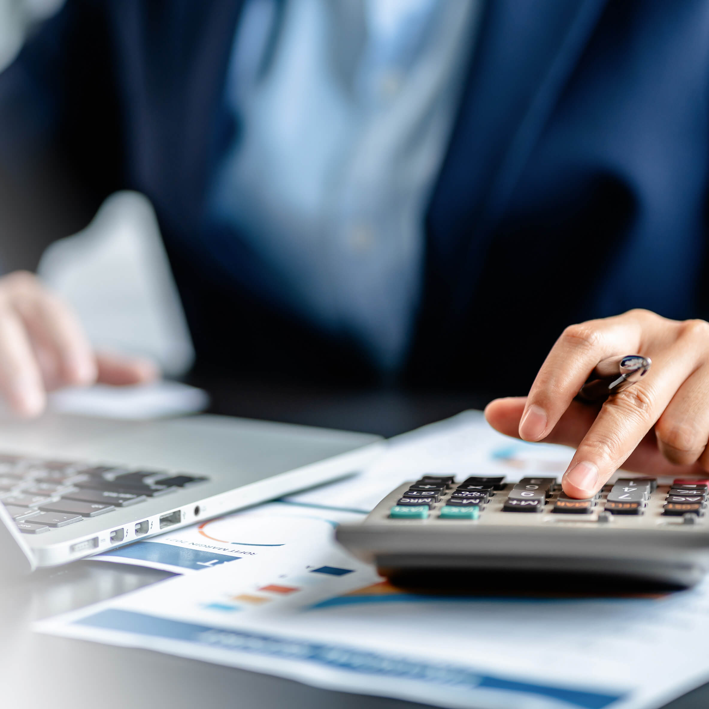 Profissional realizando cálculos financeiros em calculadora e notebook para avaliação de vida útil do imobilizado