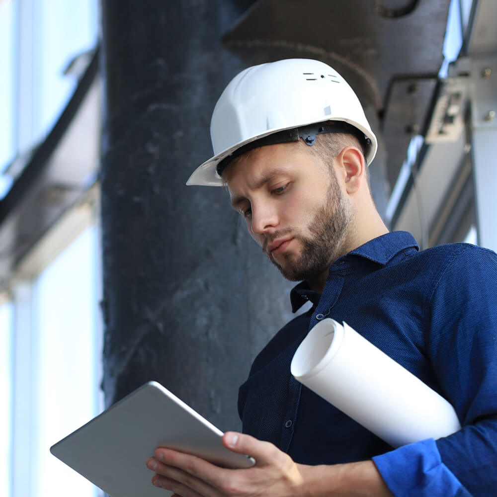 Engenheiro com capacete analisando tablet durante avaliação de bens 