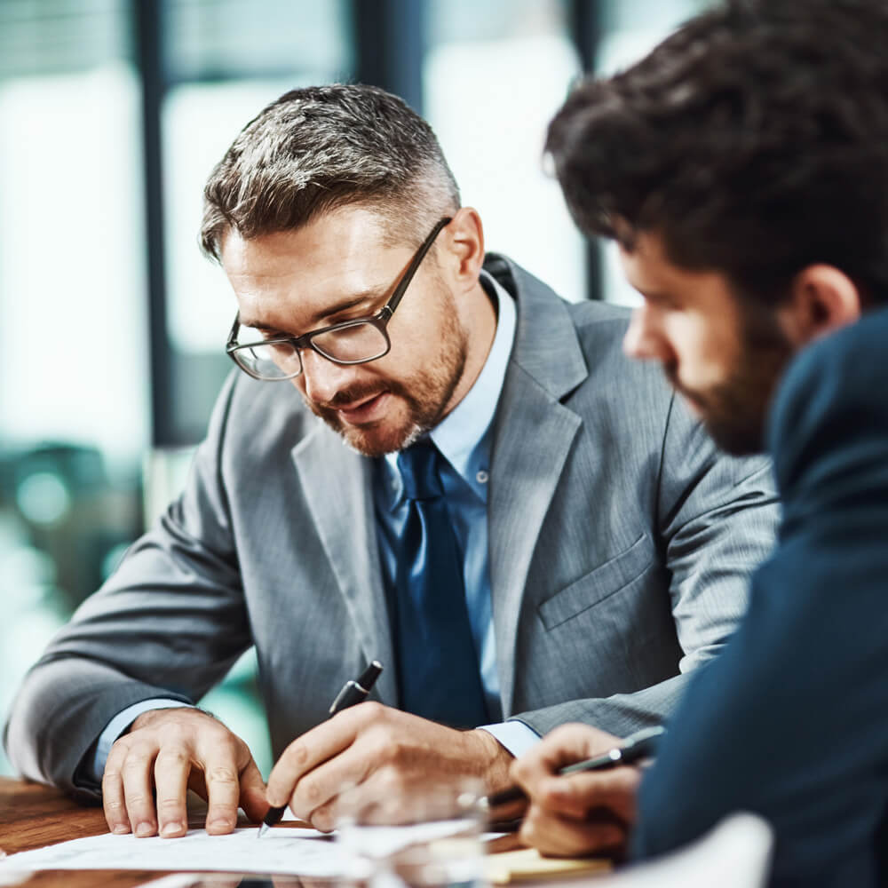 Profissionais analisando documentos e assinando relatório durante apuração de tributos relacionados ao ativo imobilizado
